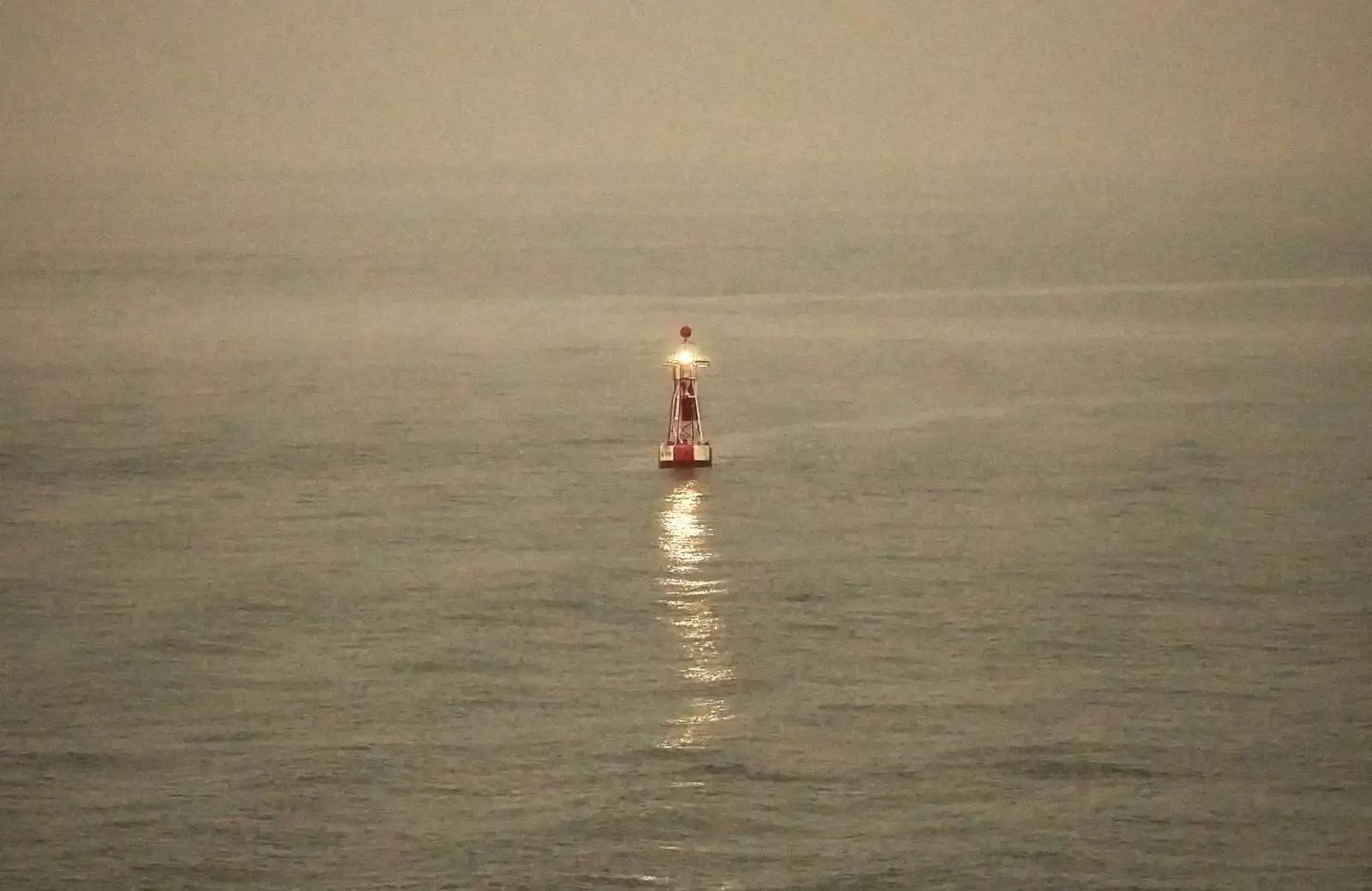 A light buoy flashing in fog off the north pier